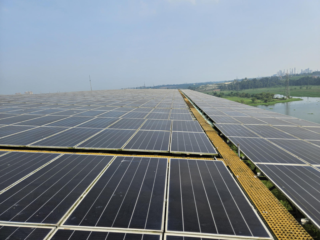 Weitläufiges Flachdach eines Campusgebäudes der RSET in Kochi, nahezu vollständig mit Photovoltaikmodulen belegt. Teil der 321-kWp-PV-Anlage des Hochschulcampus, im Hintergrund tropische Vegetation unter leicht bewölktem Himmel.
