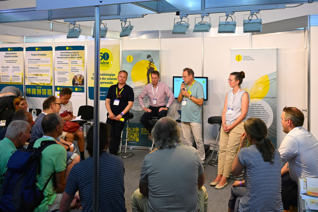 Podiumsgespräch am DGS-Stand auf der Intersolar Europe 2026: Vier Teilnehmende diskutieren vor Publikum im Stuhlkreis.
