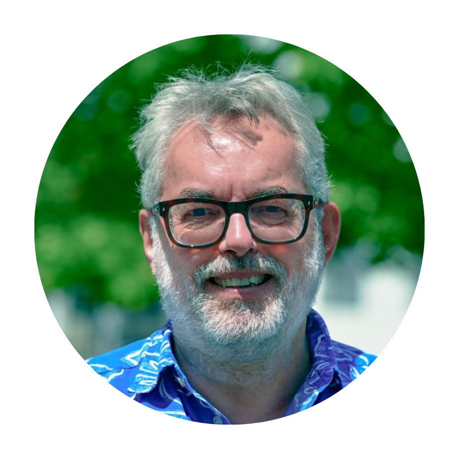 Porträtfoto von Torsten Lütten, Vizepräsident der DGS, lächelnd, mit grauem Vollbart und Brille, in einem blauen gemusterten Hemd, vor einem grünen Naturhintergrund.