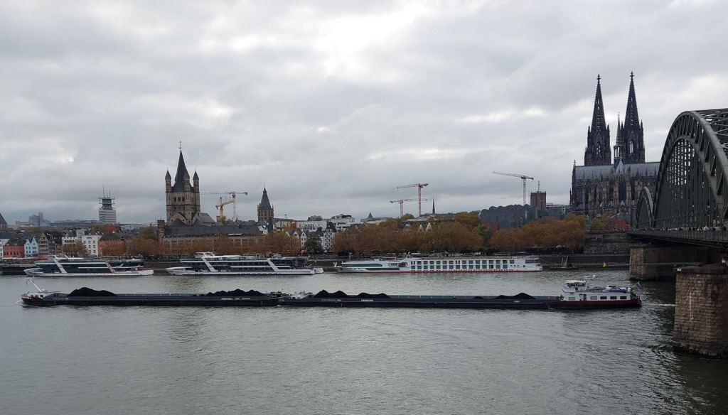 Kohlefrachtschiff auf dem Rhein bei Niedrigwasser vor der Kölner Altstadt mit Dom und Hohenzollernbrücke