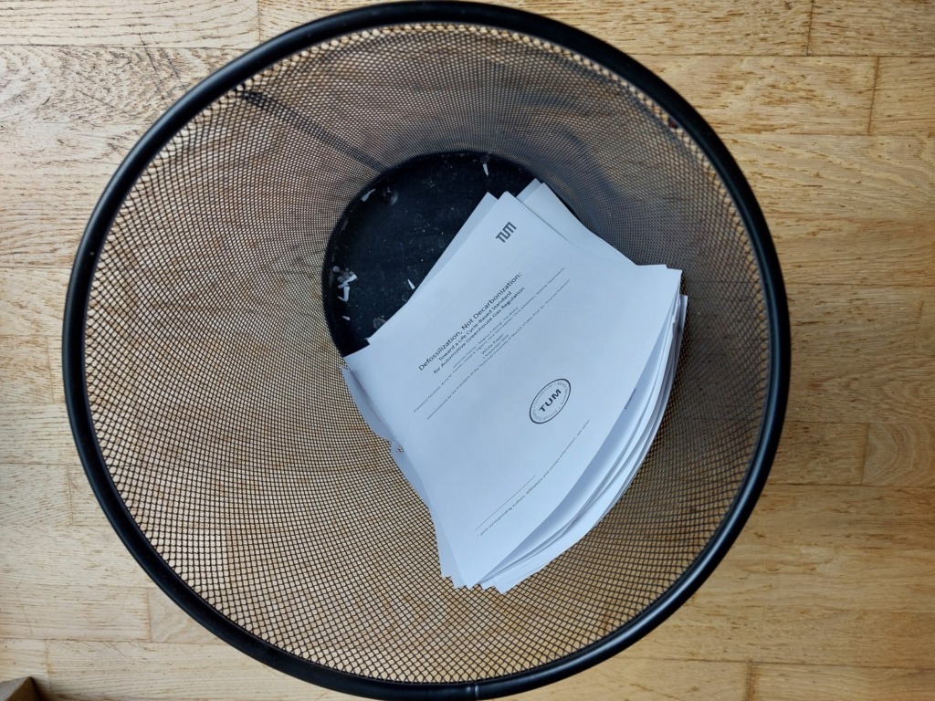 TUM-Studie zu E-Autos als ausgedrucktes Whitepaper zerknüllt im Papierkorb