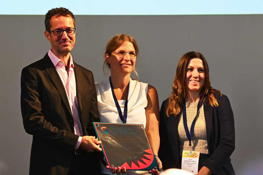Preisverleihung des SHC Solar Award 2026 auf der EuroSun2026 in Freiburg: Drei Personen halten gemeinsam die Award-Plakette.