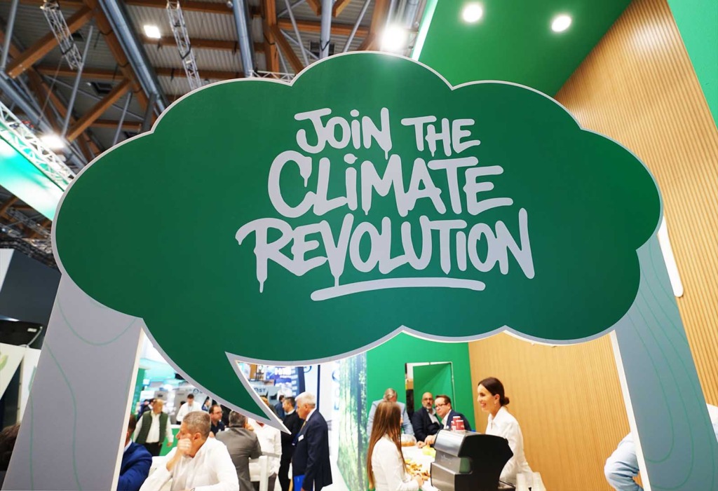 Grüne Sprechblase mit der Aufschrift „Join the Climate Revolution“ über einem Messestand auf der Chillventa 2026 in Nürnberg, darunter Besucherinnen und Besucher im Gespräch.