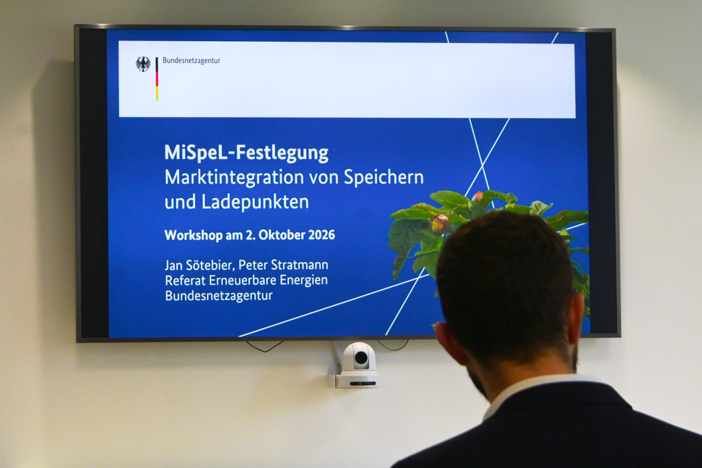 Bildschirm mit der Titelfolie der Bundesnetzagentur zur MiSpeL-Festlegung beim Workshop am 2. Oktober 2026 in Bonn, davor ein Zuschauer von hinten